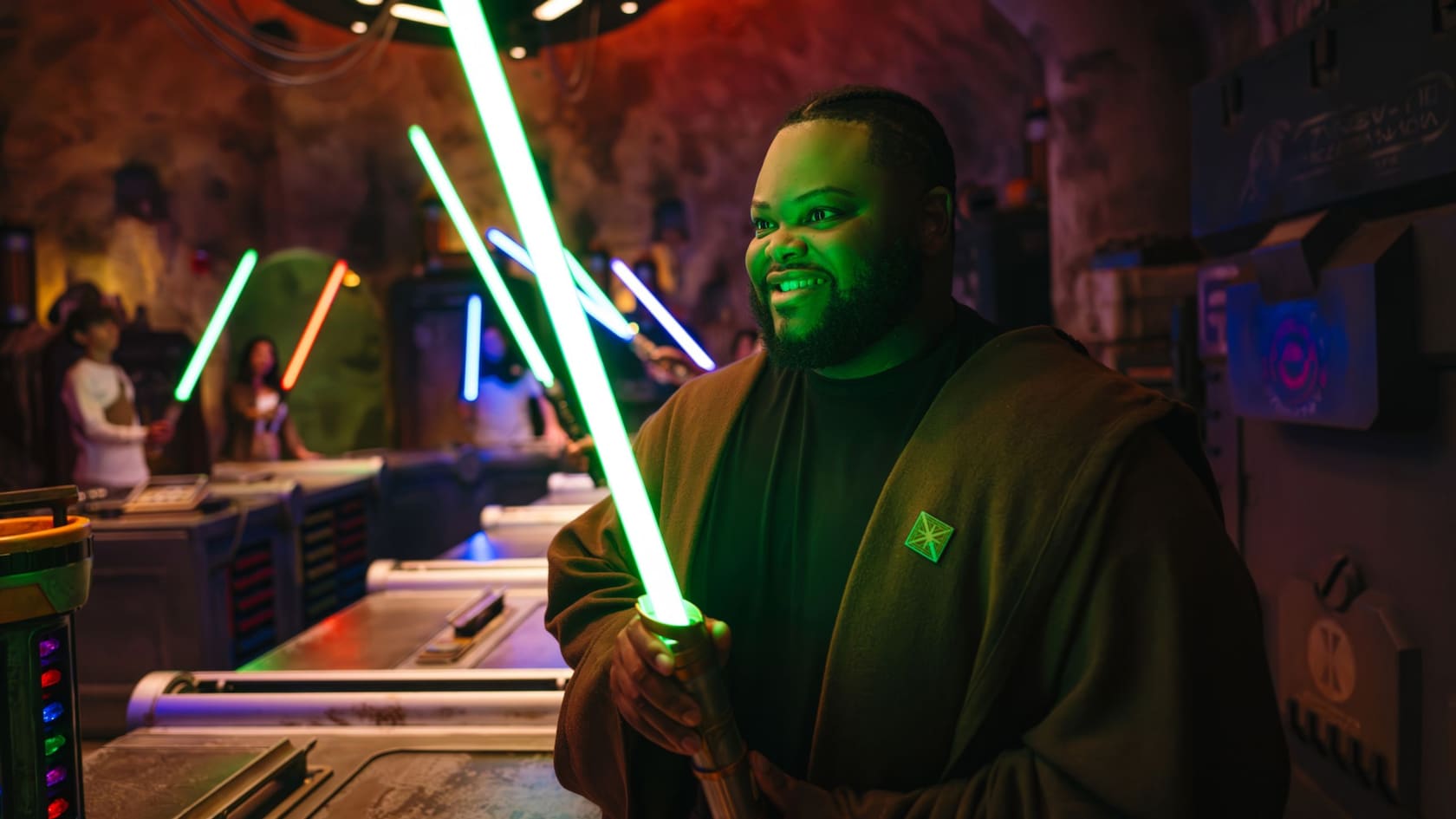 A guest in a Jedi robe holds a glowing lightsaber inside Savi's Workshop at Star Wars: Galaxy's Edge