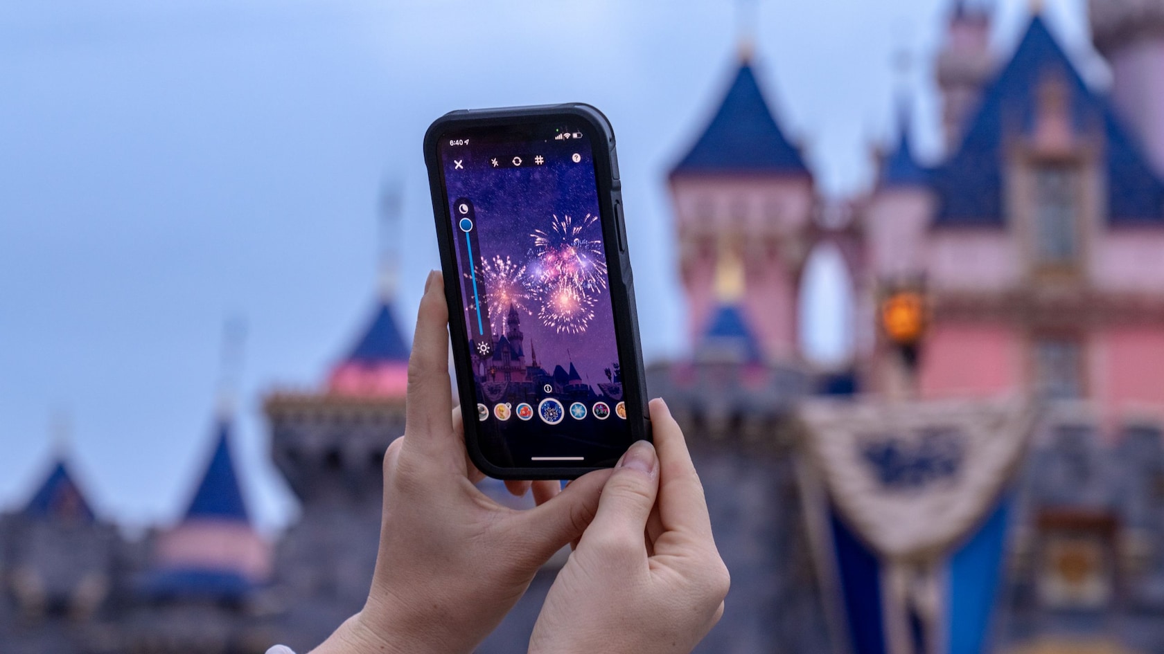 A Guest’s mobile phone captures an image of Sleeping Beauty Castle with added augmented reality fireworks