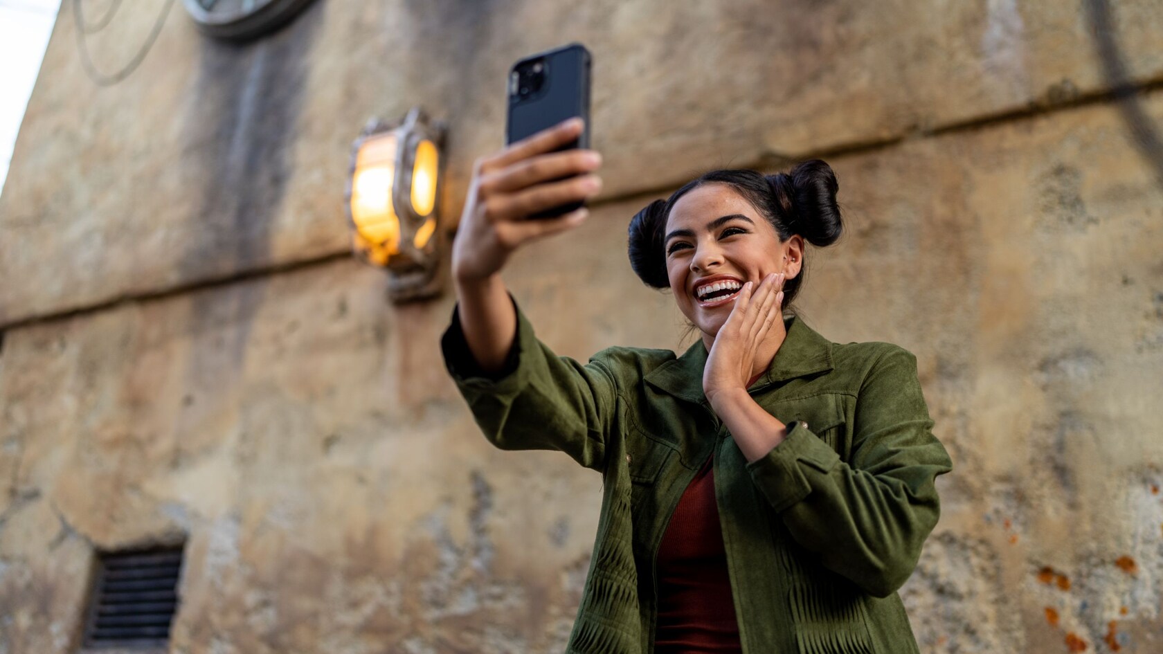 A Guest with a Princess Leia hairstyle poses for a selfie at Star Wars: Galaxy’s Edge