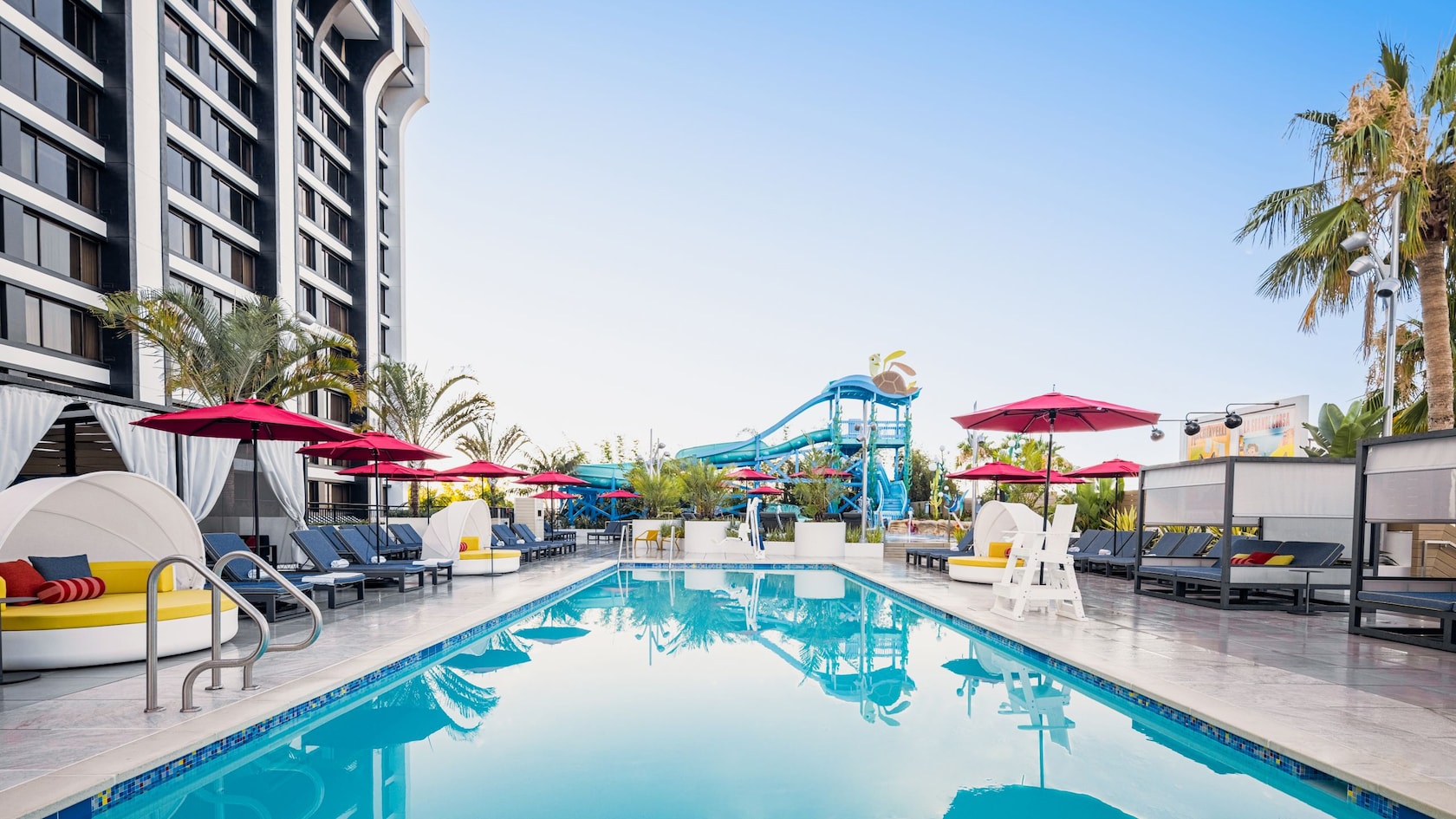 A pool surrounded by lounge chairs, sofas and umbrellas