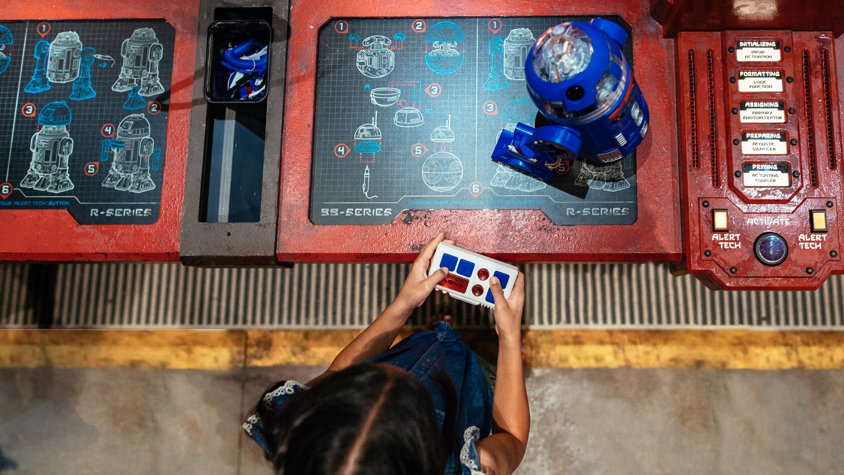 Using a remote control, a girl operates a droid she assembled at Droid Depot