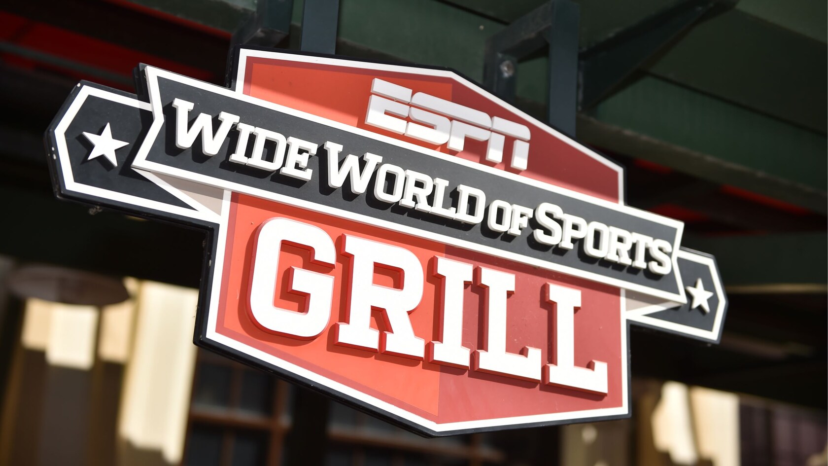 The signage for ESPN Wide World of Sports Grill hanging in front of a window