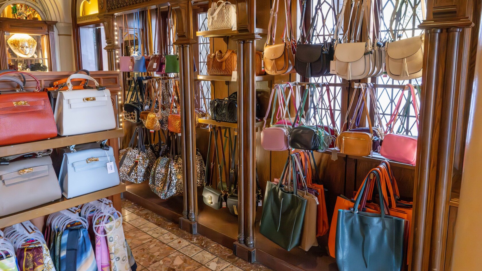 A wooden shelf and hanger inside of Il Bel Cristallo at Epcot displaying handbags