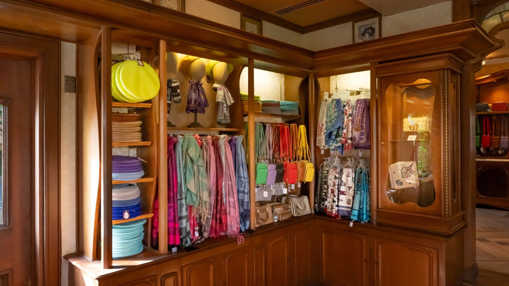 A wooden shelf and hanger displaying a variety of clothing and personal accessories in Plume Et Palette at Epcot