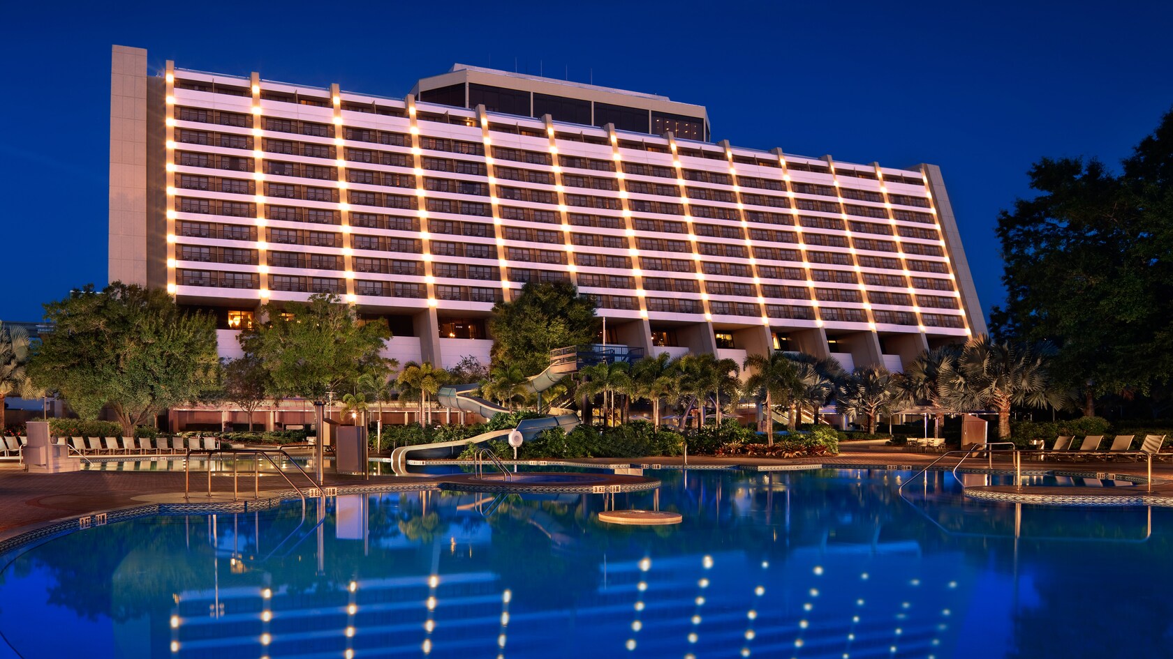 A poolside view of the rear of Disney's Contemporary Resort, lit up at night