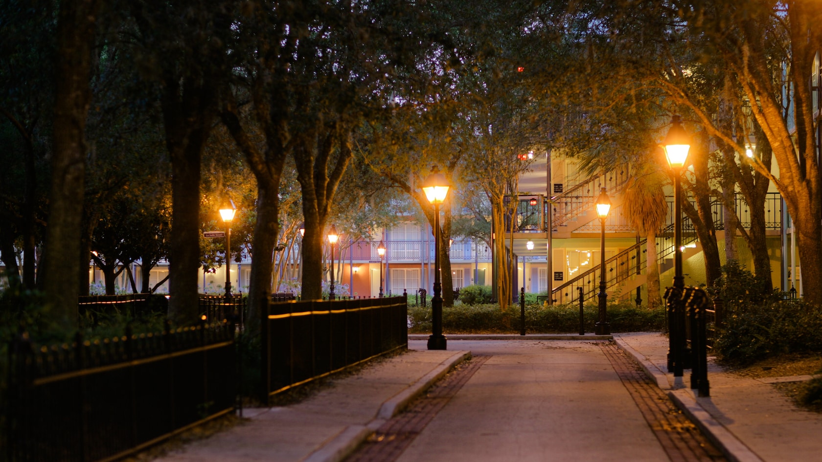 A tree-lined lane lit with antique-style street lamps