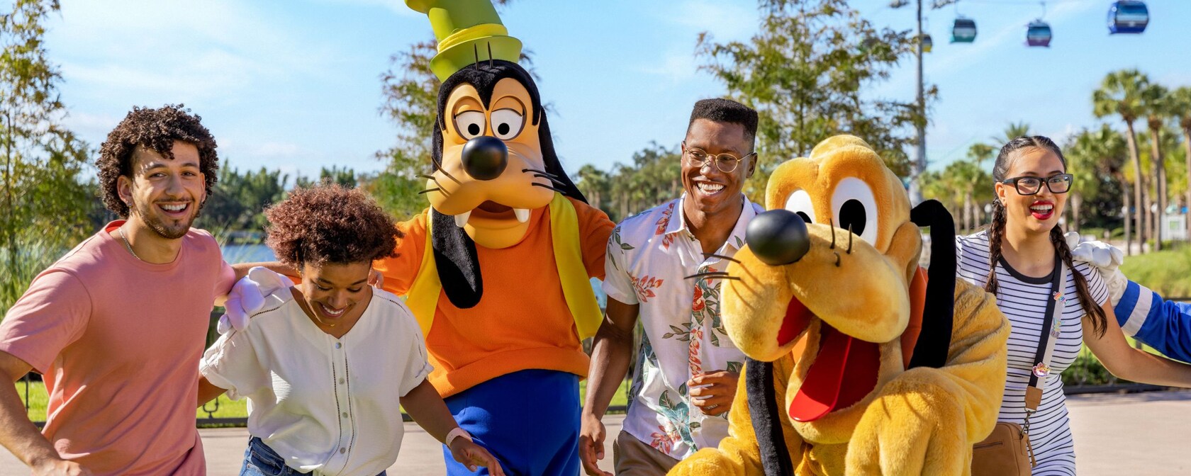 Guests smile and pose for a photo with Goofy and Pluto