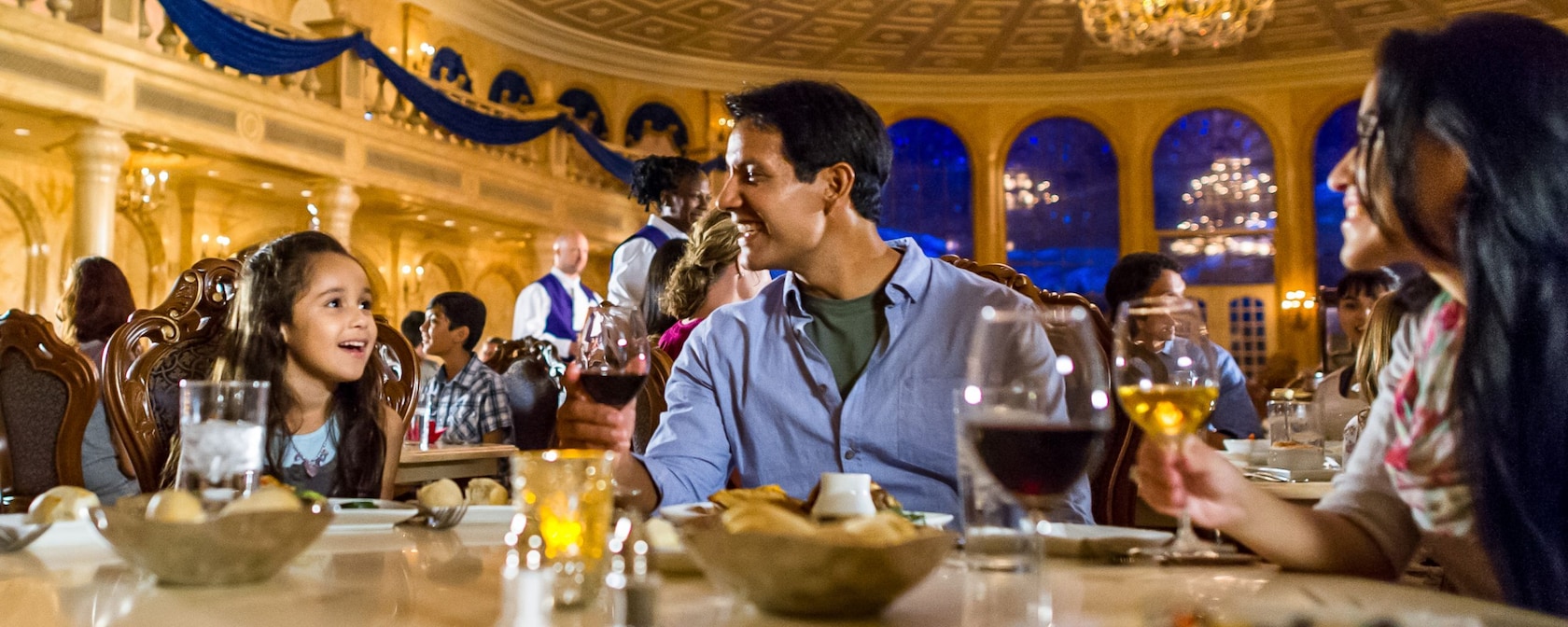 A young girl dining with her parents in The Grand Ballroom at Be Our Guest Restaurant