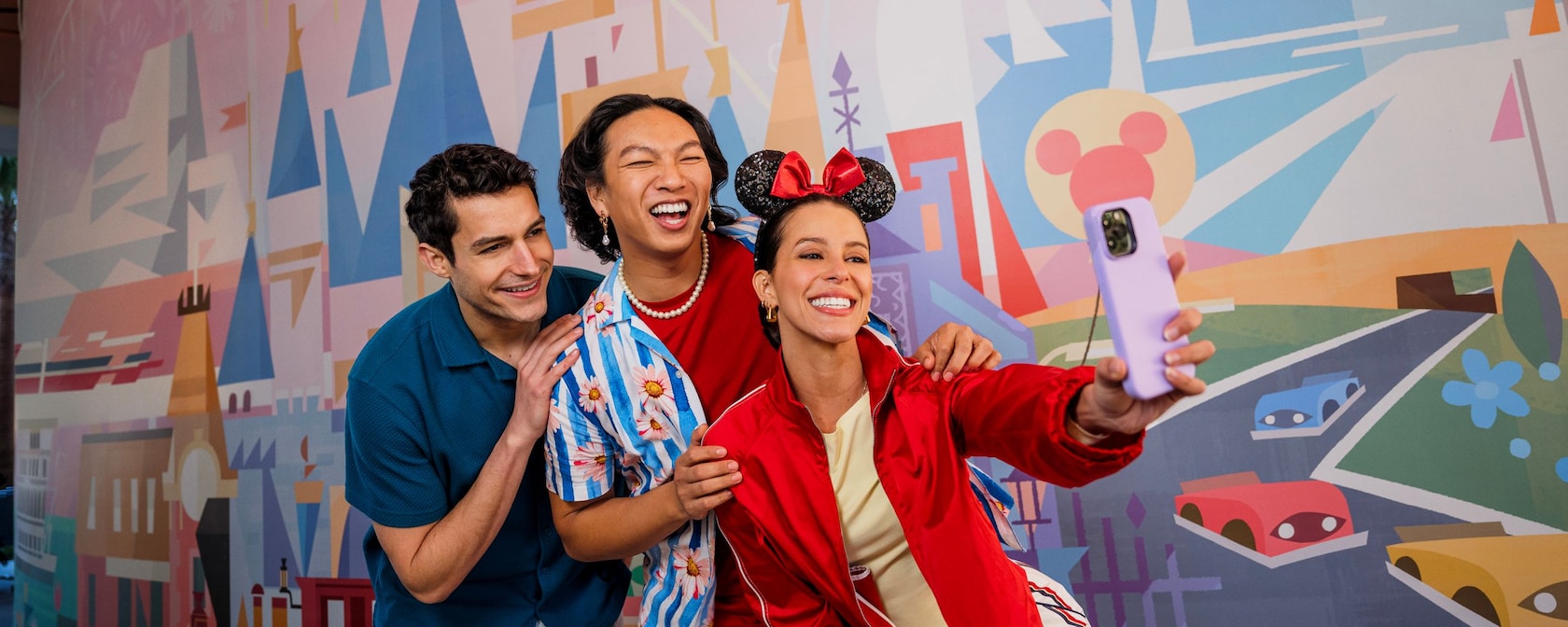Three friends taking a selfie in front of a mural at Palm Breeze Bar in the Disneyland Hotel