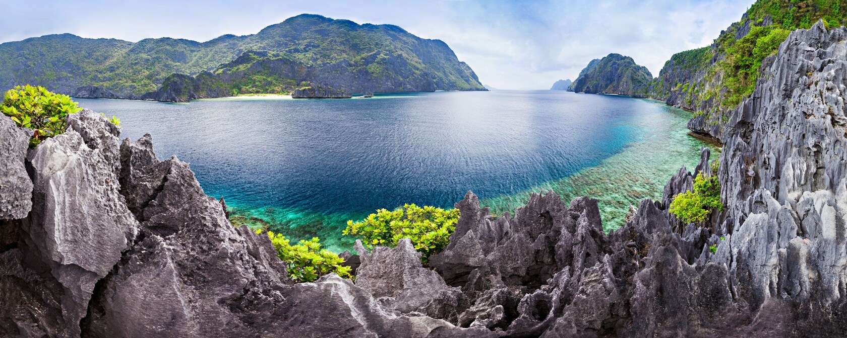 Striking, jagged rock formations and colorful foliage surround a tropical lagoon in the Philippines