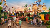 Una familia pasea felizmente por Toy Story Land mientras un grupo de amigos posa para una selfi cerca de Woody