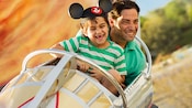 A father and his son, wearing a Mickey ear hat, have a blast on the Astro Orbiter