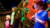 彼得潘（Peter Pan）在一艘海盗船操纵舵轮，温蒂（Wendy）、迈克尔（Michael）和约翰（John）分别站在他的两旁。  