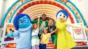 A family poses with Joy and Sadness from Inside Out
