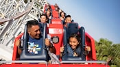 A father and daughter smile with excitement while riding the Incredicoaster