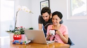 A couple looks at a laptop while sipping coffee