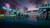 Gas station-themed entrance to Flo’s V8 Café lit with neon signs at night