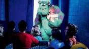 Guests ride through Monstropolis in a taxi and pass Sully holding Boo close