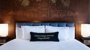 ディズニーランド・ホテルのゲストルーム内の眠れる森の美女の城が描かれたヘッドボードと飾り枕