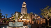 A fountain near a street, trees and a marque with a sign that reads Carthay Circle