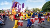 A parade with drummers, Pluto, and Mickey Mouse and Minnie Mouse on a float