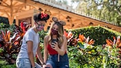 Two people wearing Minnie Mouse ears look at a smartphone