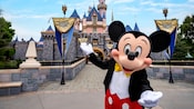 Mickey Mouse stands in front of Sleeping Beauty Castle