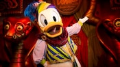 Donald Duck stands in front of cobra statues