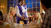 A waitress in a restaurant brings a chocolate dessert to a girl, with her surprised mother looking on