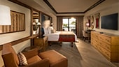 A contemporary master bedroom with a chair, wall art, bedside table, bed, patio, desk, mirror, dresser and TV