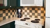 A stove, microwave and coffee maker in a tiled kitchen area