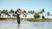 ヤシの木が植えられたビーチのそばのラグーンで、小さな男の子を高く抱え上げている父親 ヤシの木が植えられたビーチのそばのラグーンで、小さな男の子を高く抱え上げている父親
