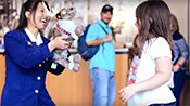A hotel clerk presents a plush toy moose to a young girl