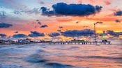 A view of Galveston Island Pleasure Pier in its entirety, under a bright but cloudy sky A view of Galveston Island Pleasure Pier in its entirety, under a bright but cloudy sky