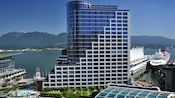 A Disney cruise ship docked next to the glass and steel Fairmont Waterfront Vancouver