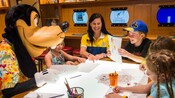 Goofy observa mientras un asesor de Disney trabaja en la creación de un proyecto de arte con los niños