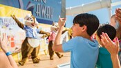 A child in a crowd raises his hands while Chip 'n' Dale perform on stage during the Sailing Away Deck Party