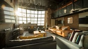 A cozy recreation room with a jumbo screen TV, large windows and overstuffed chairs and couches