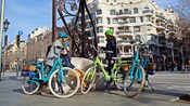 3 cyclists taking a break near a sculpture in Barcelona, Spain