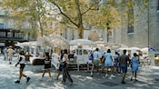 People perusing works of art at an outdoor art fair held in a Spanish plaza