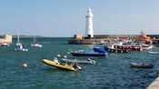 A lighthouse on the edge of a harbor lined with boats
