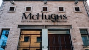 A historic stone building with a sign that reads McHughes, Established 1711 in Belfast