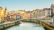 Uma ponte sobre um rio em uma cidade europeia com arquitetura do século XIX