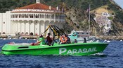 A speedboat with the word Parasail on its side sailing next to a circular art deco building