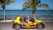 4 passengers cruising in an open top beach buggy next to a tropical seashore