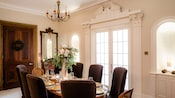 An elegant dining room with a chandelier, French doors and a table set for 8