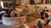 Os hóspedes assistem a uma demonstração de um cavalo puxando uma roda em torno de um moinho de pedras