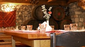 The interior of a rustic restaurant reveals a wooden table set for 6 guests