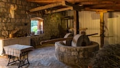 A rustic kitchen with a large stone mill