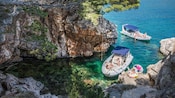 Guests relaxing in 2 inflatable boats in a rocky sea cove